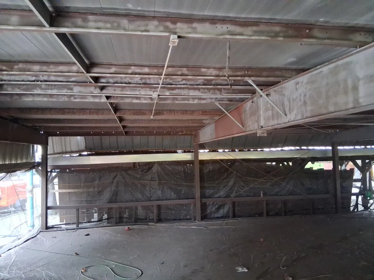 Structural steel framework and beams being sandblasted with plastic containment sheeting